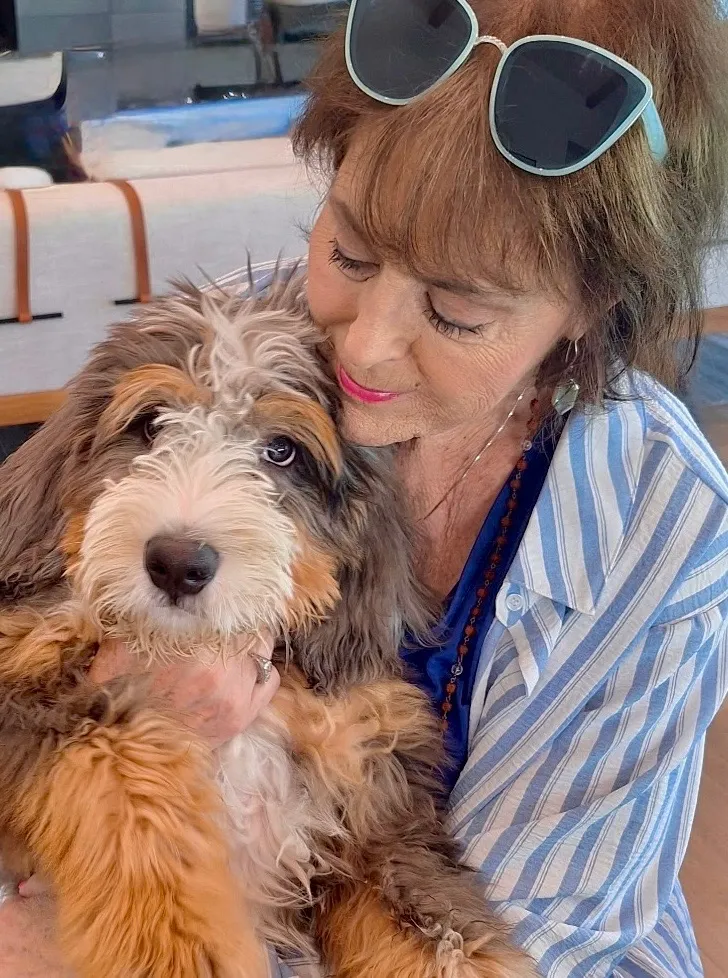 Barbie Baugh, owner of Pawsatively Perfect Pet Care, gently holding a puppy at home