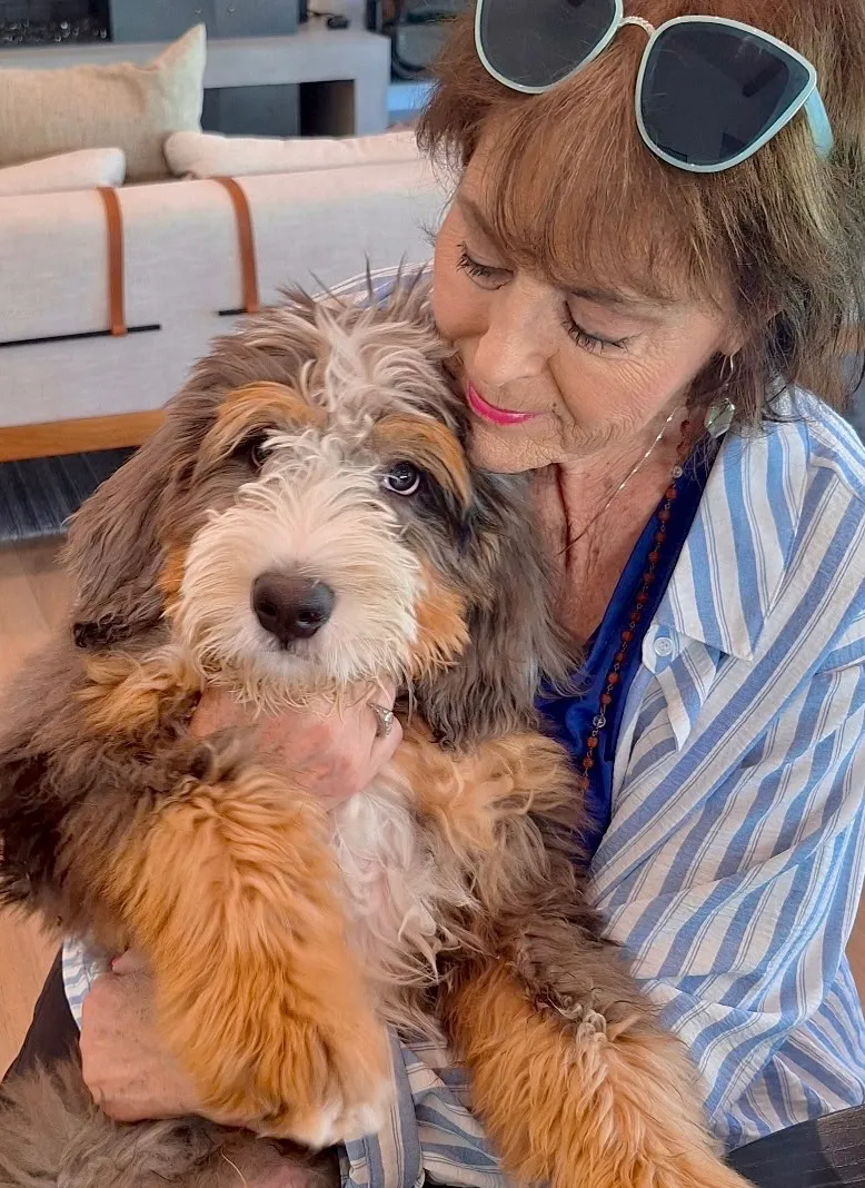 Barbie Baugh, owner of Pawsatively Perfect Pet Care, gently holding a puppy at home
