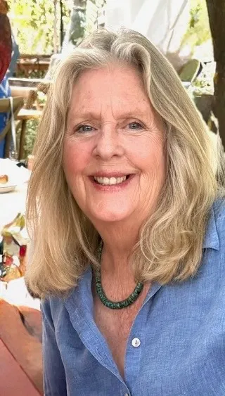 Diane smiling in a blue shirt with a teal necklace