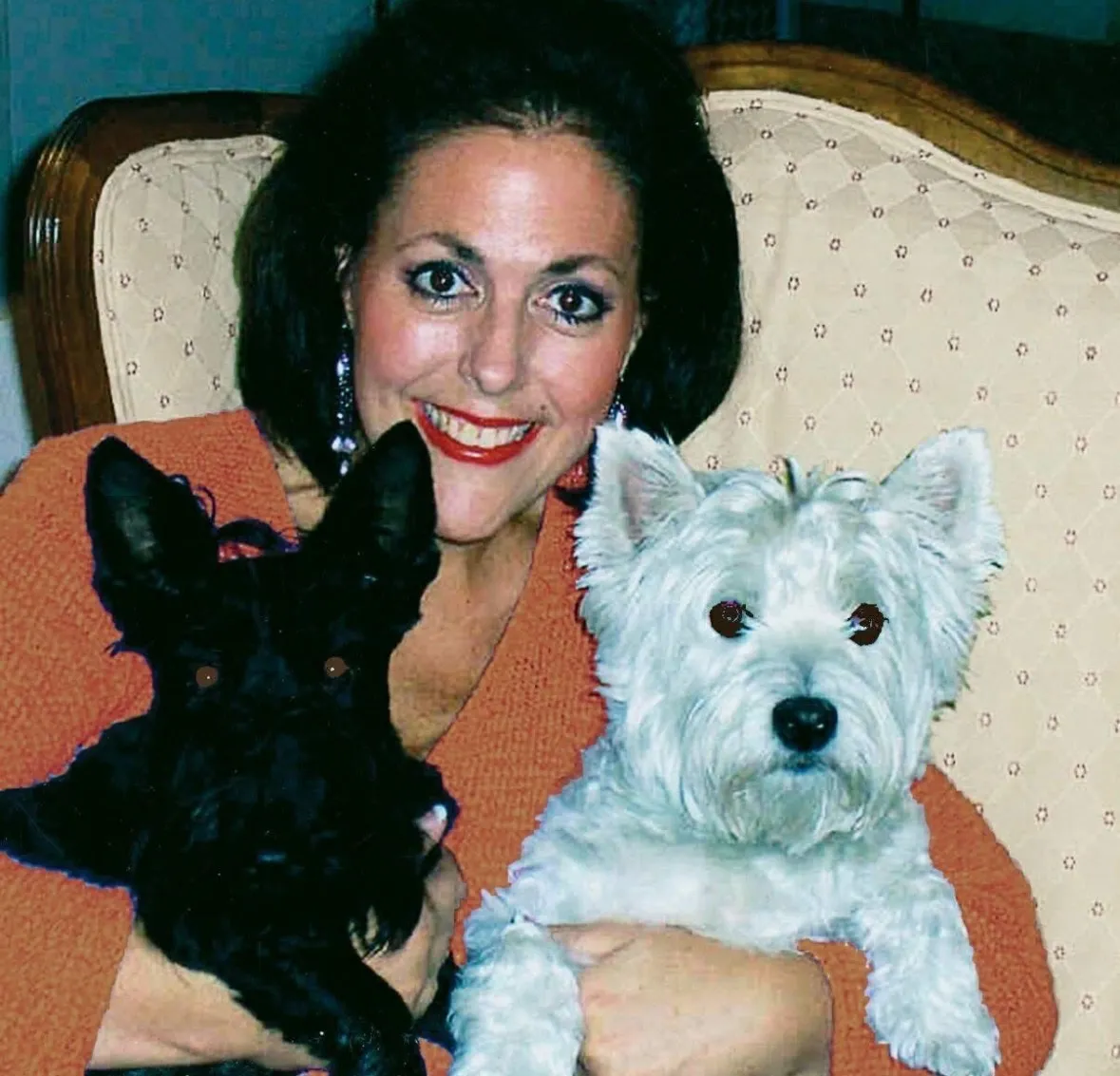 Barbie Baugh smiling while holding a black Scottish Terrier and a white West Highland Terrier