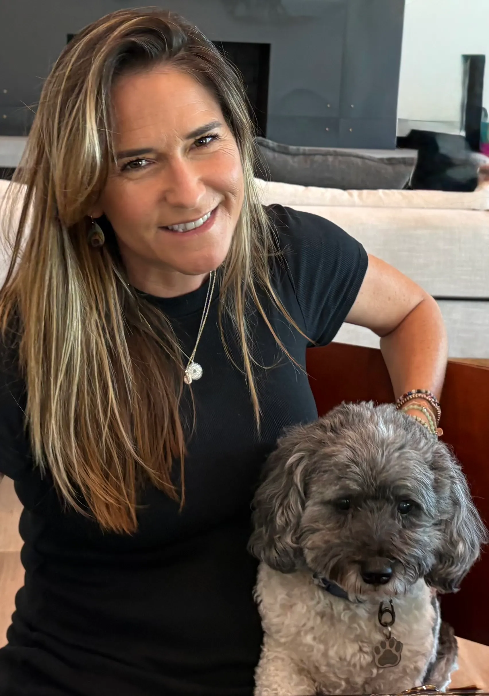 Nikki smiling with a grey curly-haired dog